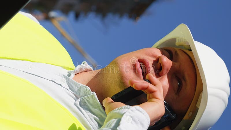 Pantalla vertical : inspector de edificios hablando por teléfono en el lugar de la construcción