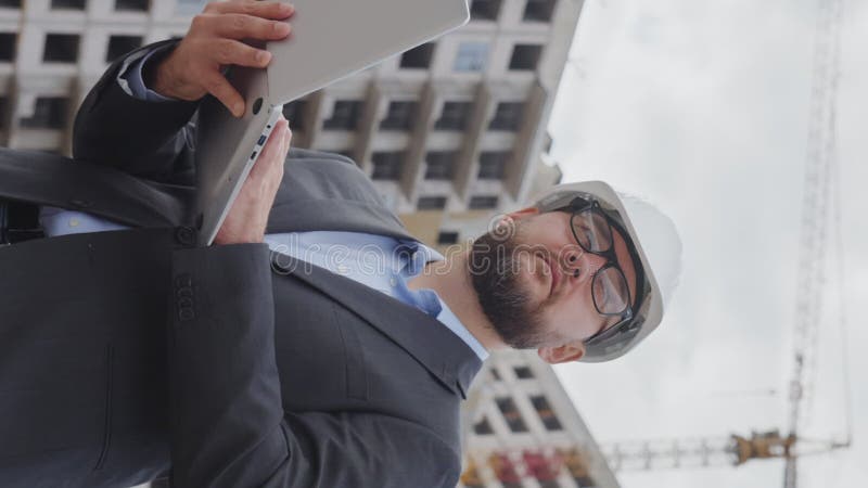 Pantalla vertical : inspector de edificios haciendo notas sobre el portátil en el lugar de construcción