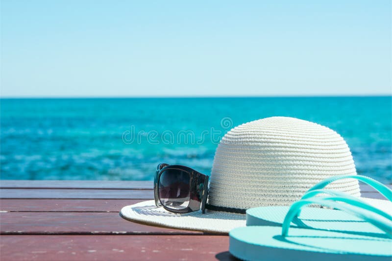 Pantoufles de lunettes de soleil de chapeau sur le fond de mer de ciel bleu et de turquoise Relaxation de voyage de vacances d'ét image stock Pantoufles de lunettes de soleil de chapeau sur le fond de mer de ciel bleu et de turquoise Relaxation de voyage de vacances d'ét image stock