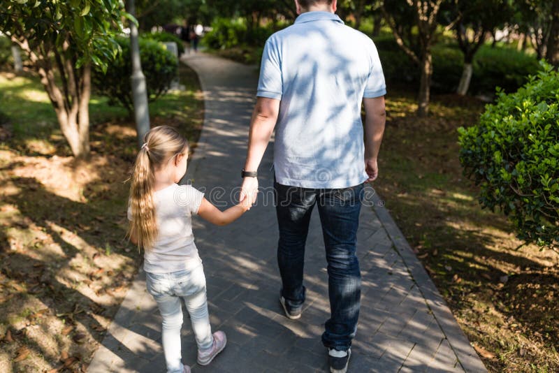 Pap? che tiene la figlia delle mani con amore e che cammina nel parco Concetto 'nucleo familiare' fotografie stock libere da diritti Pap? che tiene la figlia delle mani con amore e che cammina nel parco Concetto 'nucleo familiare' fotografie stock libere da diritti