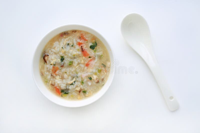 Papa de aveia para o comida para bebê na bacia e na colher cerâmicas brancas no fundo branco fotografia de stock royalty free Papa de aveia para o comida para bebê na bacia e na colher cerâmicas brancas no fundo branco fotografia de stock royalty free