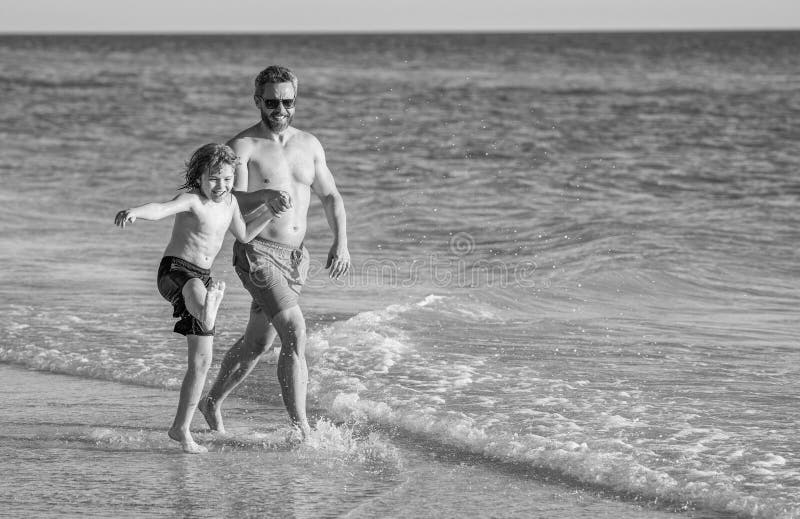 Papa und Sohn laufen am Strand. Kinderbindung des Vaters im Sommer. Besondere Momente zwischen Papa und Sohn bei lizenzfreies stockfoto