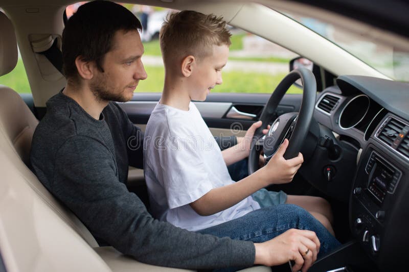 Glücklicher Vater und Sohn spielen mit dem Lenkrad im Auto, lizenzfreies  Stockfoto