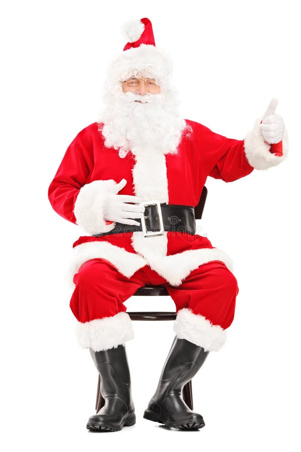 Papai Noel feliz que senta-se em uma cadeira de madeira e que dá um polegar u imagens de stock royalty free Papai Noel feliz que senta-se em uma cadeira de madeira e que dá um polegar u imagens de stock royalty free
