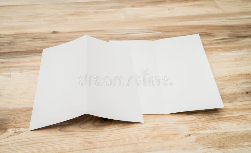 Papel modelo branco dobrado ao meio sobre textura de madeira imagens de stock