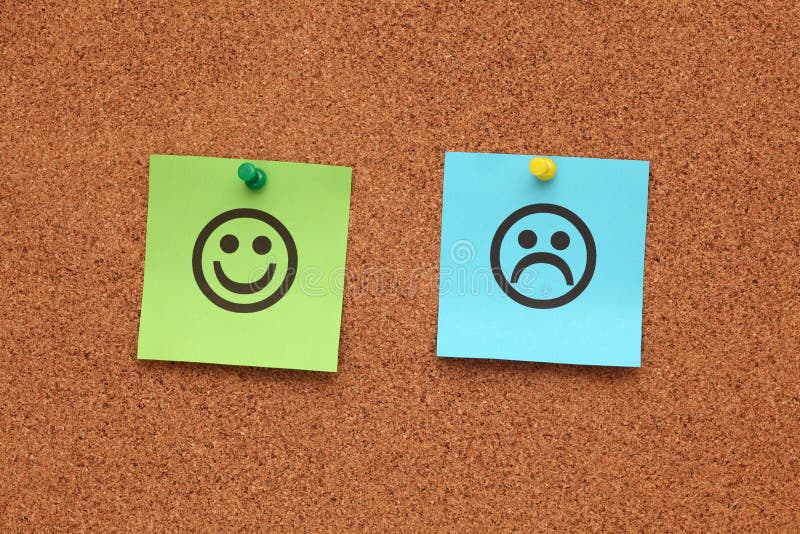 Papel com carinhas felizes e tristes num quadro de cortiça fotografia de stock