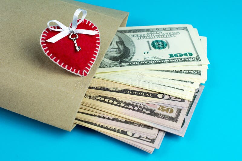 Paper bag with money on a blue background. decorative hearts made of red fumirana sewn with a white thread a symbol of a gift for St. Valentine`s Day. selective . close-up. Paper bag with money on a blue background. decorative hearts made of red fumirana sewn with a white thread a symbol of a gift for St. Valentine`s Day. selective . close-up