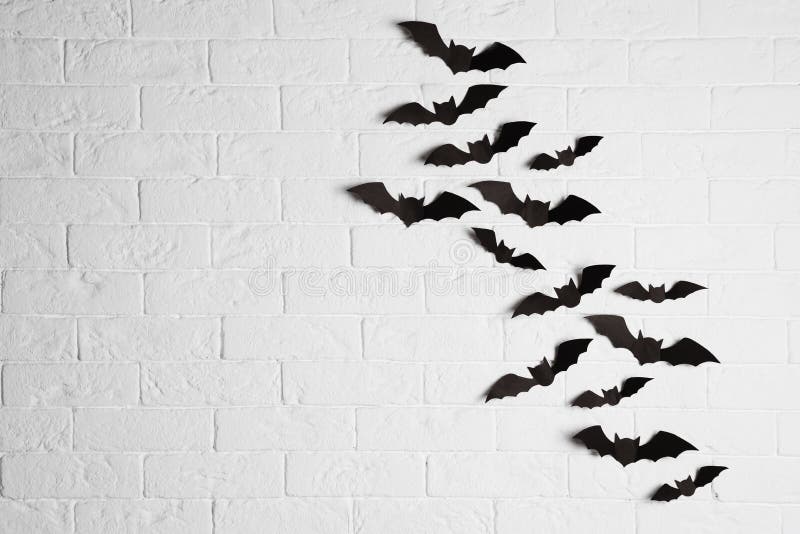 Paper bats on brick wall with space for text