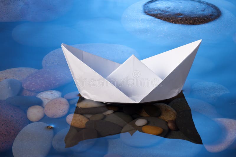 Paper Boat. A white paper boat floating on a blue water surface Paper Boat. A white paper boat floating on a blue water surface