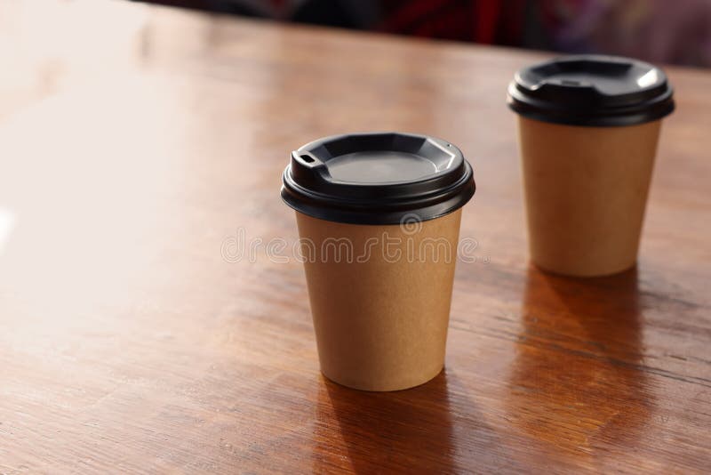 Paper coffee cups with plastic lids on wooden table stock photo