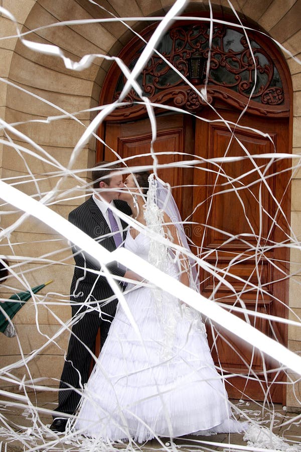 A bride and groom behind paper confetti