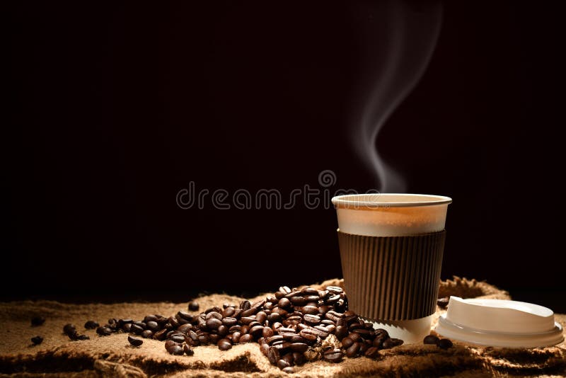 Paper cup of coffee with smoke and coffee beans