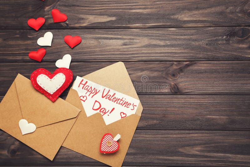 Paper envelopes with hearts and text Happy Valentines Day on wooden table