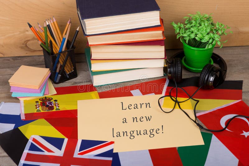 Paper with text & x22;Learn a new language!& x22;, flags, books, headphones, pencils