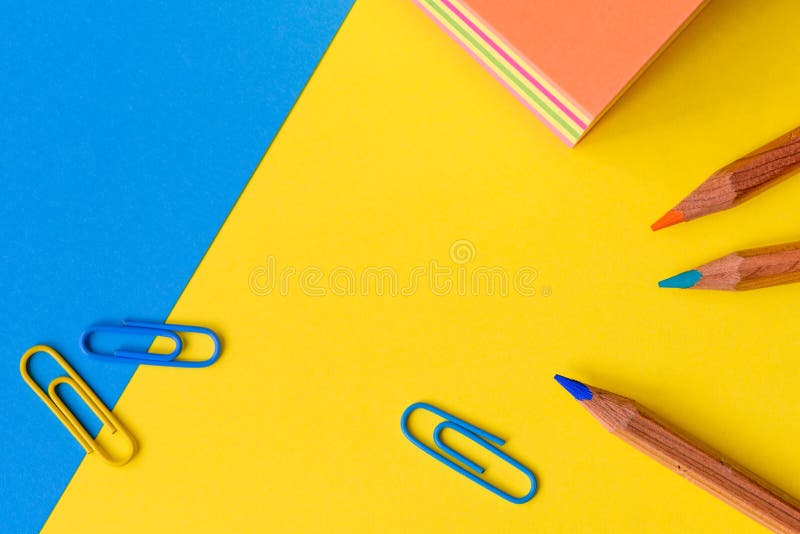 Paperclips, pencils and a memo block isolated against a blue and