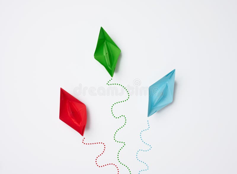 Paper boats move in different directions on a white background. Differing opinions, ineffective management. Disunity of the collective. Paper boats move in different directions on a white background. Differing opinions, ineffective management. Disunity of the collective.