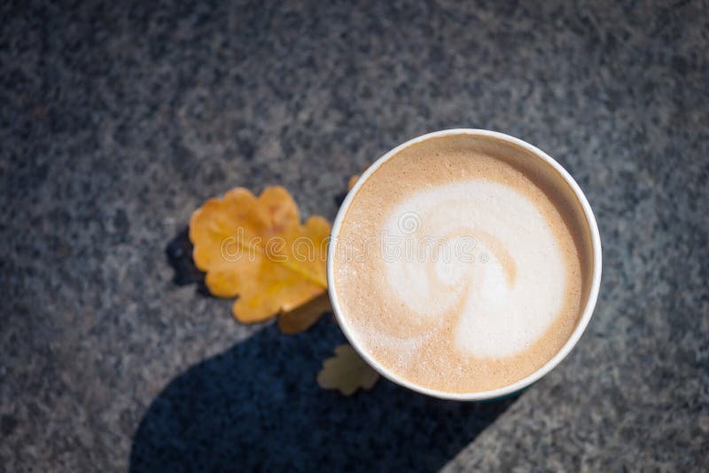 Papieren blauwe koffiebeker op de herfstherfstbladeren en steengrijze achtergrond stock fotografie Papieren blauwe koffiebeker op de herfstherfstbladeren en steengrijze achtergrond stock fotografie