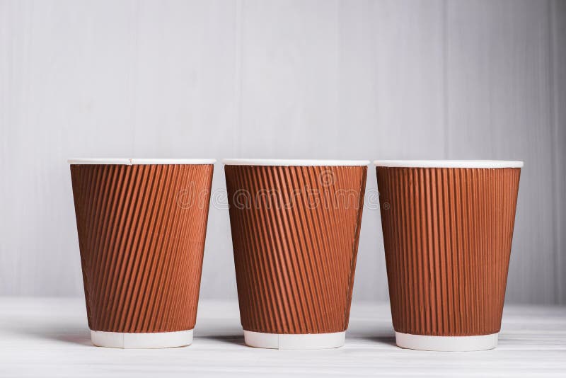 Papierkaffeetassen auf weißer hölzerner Tabelle, Mitnehmergetränkbehälter