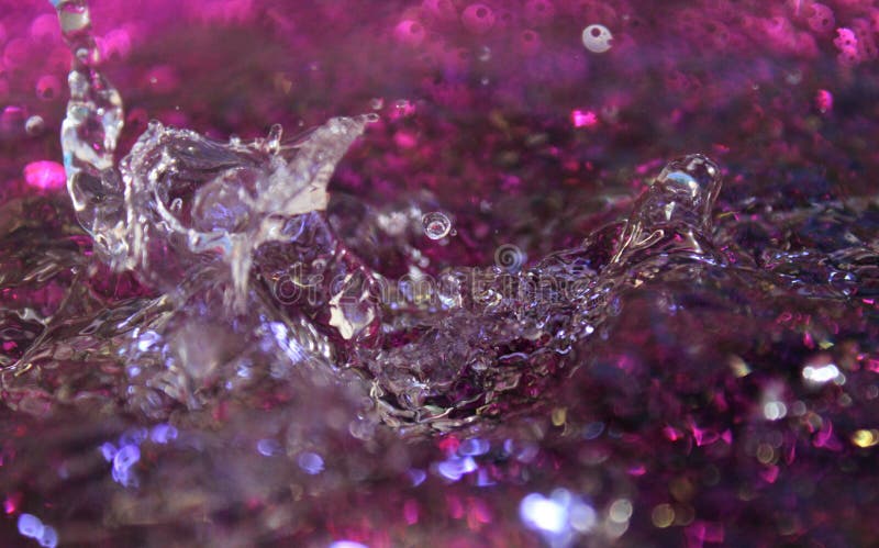 Frozen movement of water. Drops of water falling and splashing, and others suspended in the air. Sparkles, reflections of light. Dark purple color with silver touches. Frozen movement of water. Drops of water falling and splashing, and others suspended in the air. Sparkles, reflections of light. Dark purple color with silver touches.