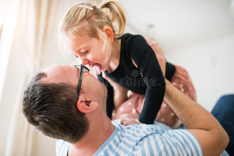 Pappa leker med en liten dotter som håller henne ovanför honom. flicka och pappa har kul. royaltyfria bilder