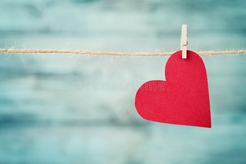 Pappers- hjärta som hänger på rad mot turkosträbakgrund för valentindag arkivfoton