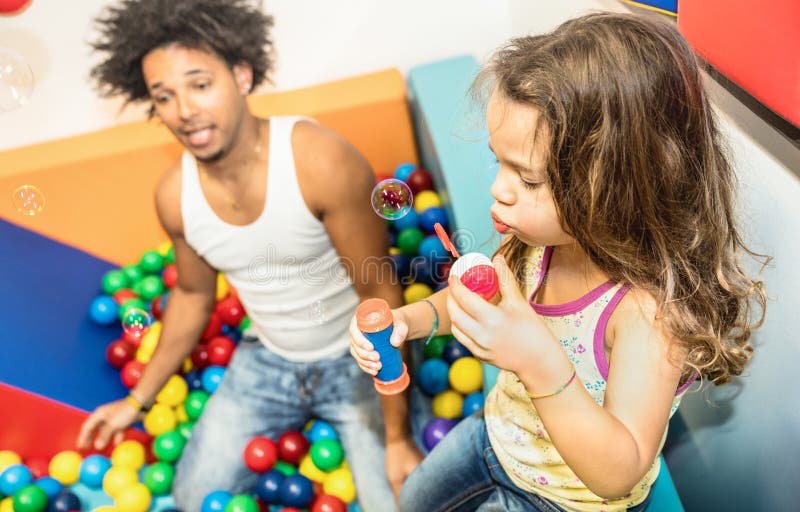 Papà dell'America latina che gioca con la figlia della corsa mista alla stanza dei giochi immagine stock libera da diritti Papà dell'America latina che gioca con la figlia della corsa mista alla stanza dei giochi immagine stock libera da diritti