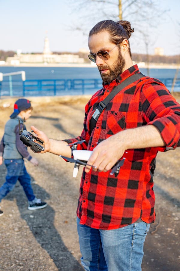 Papà e figlio che giocano con il fuco, l'uomo ed il ragazzo giocanti con il fuco di volo in parco fotografie stock Papà e figlio che giocano con il fuco, l'uomo ed il ragazzo giocanti con il fuco di volo in parco fotografie stock