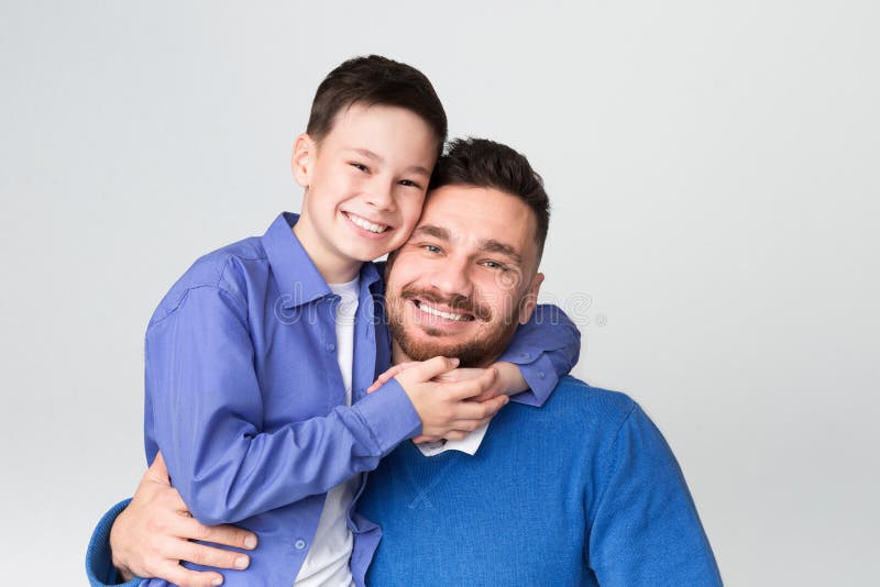 Papá alegre e hijo que abrazan y que sonríen en la cámara imagen de archivo libre de regalías Papá alegre e hijo que abrazan y que sonríen en la cámara imagen de archivo libre de regalías