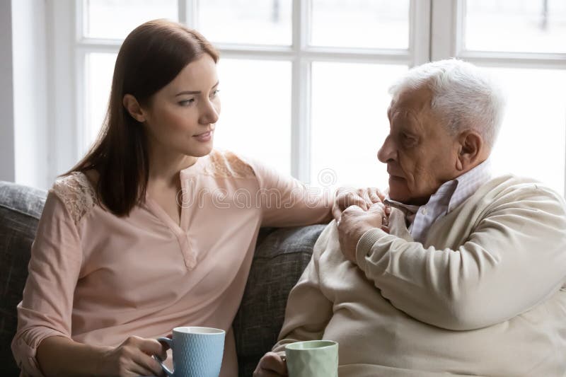 Papá anciano e hija mayor se relajan en el sofá hablando foto de archivo