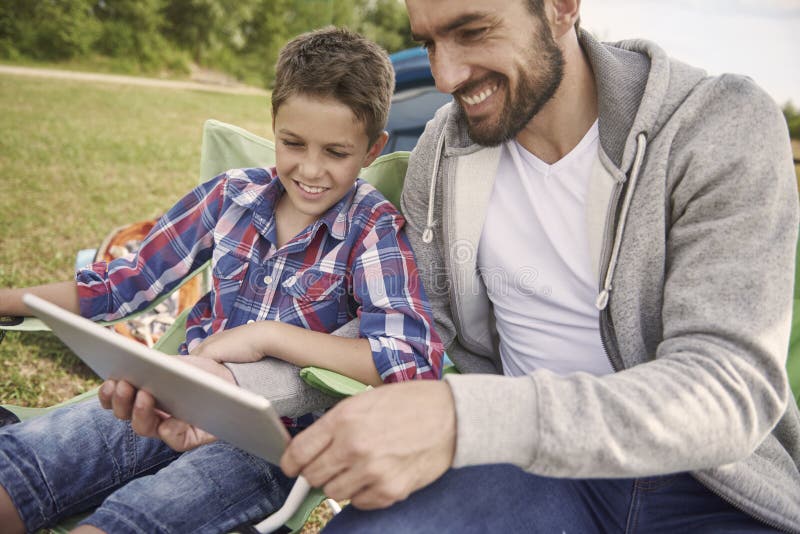Papá con su hijo que mira algo en la tableta foto de archivo Papá con su hijo que mira algo en la tableta foto de archivo