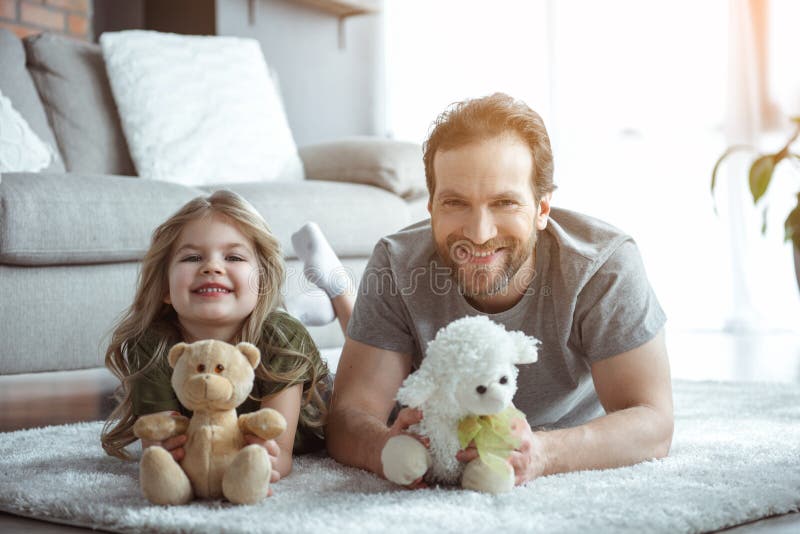 Papá emocionado y muchacha que juegan con el oso de peluche imagen de archivo libre de regalías Papá emocionado y muchacha que juegan con el oso de peluche imagen de archivo libre de regalías