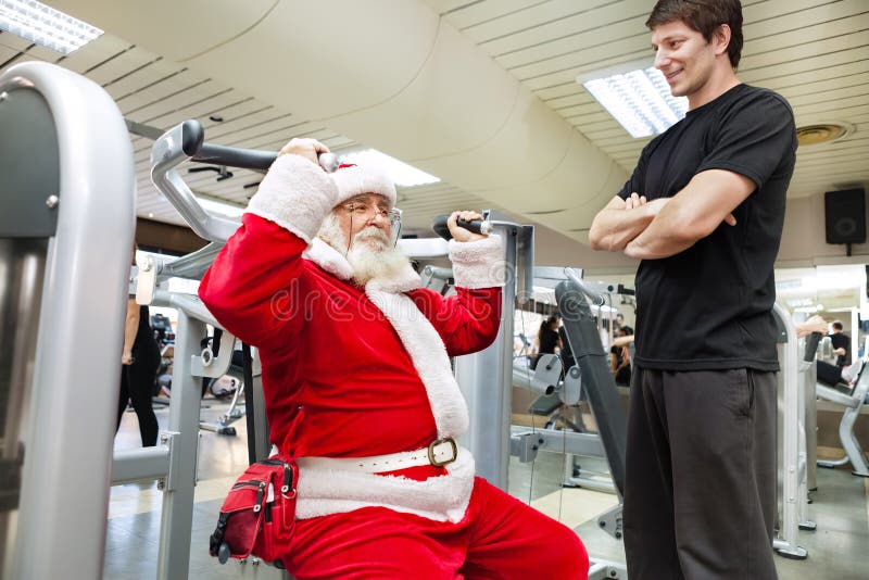 Papá Noel con el instructor personal en el gimnasio foto de archivo libre de regalías Papá Noel con el instructor personal en el gimnasio foto de archivo libre de regalías