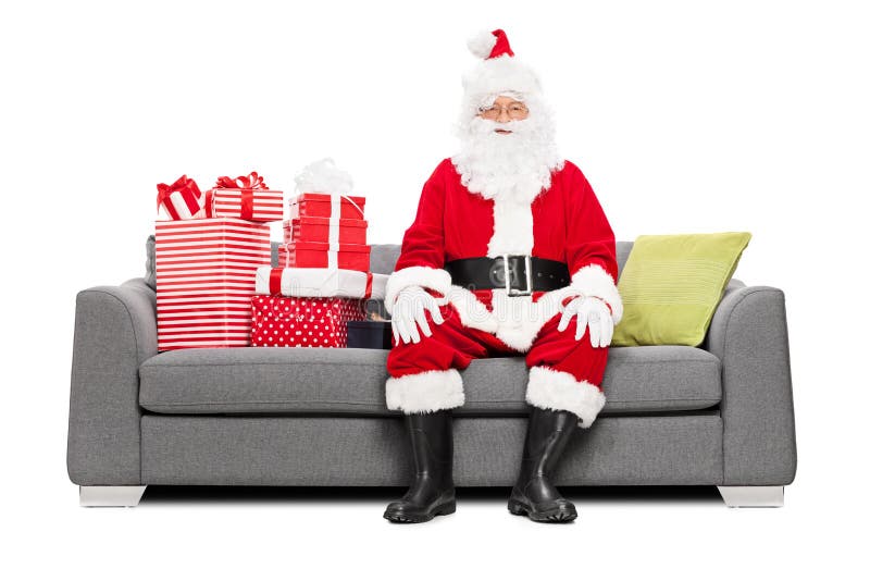 Papá Noel que se sienta en un sofá por completo de regalos de Navidad imagenes de archivo Papá Noel que se sienta en un sofá por completo de regalos de Navidad imagenes de archivo