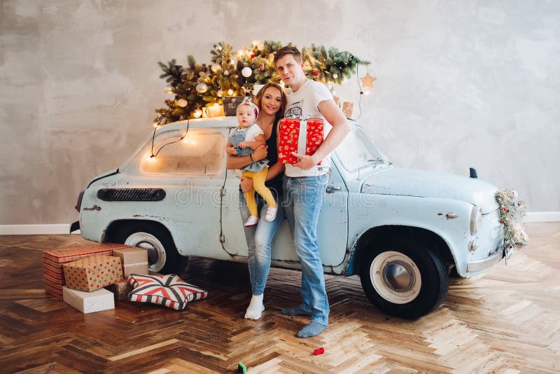 Papá que besa a la mamá rubia, que sosteniéndose encendido da a pequeña hija linda, colocándose cerca del coche retro azul fotos de archivo libres de regalías Papá que besa a la mamá rubia, que sosteniéndose encendido da a pequeña hija linda, colocándose cerca del coche retro azul fotos de archivo libres de regalías