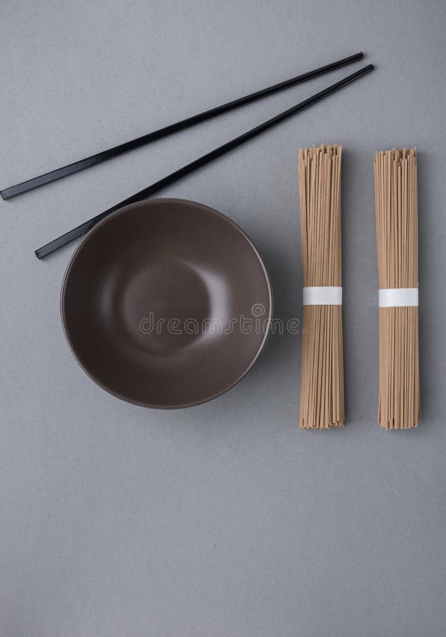 Paquets de baguettes vides foncées de bambou noir de bol de nouilles de Soba sur Grey Background Cuisine asiatique chinoise japon photographie stock libre de droits Paquets de baguettes vides foncées de bambou noir de bol de nouilles de Soba sur Grey Background Cuisine asiatique chinoise japon photographie stock libre de droits