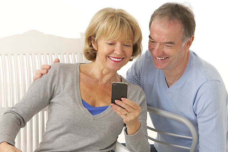 Par av pensionärer med den lyckliga mobiltelefonen - och att le royaltyfri bild Par av pensionärer med den lyckliga mobiltelefonen - och att le royaltyfri bild