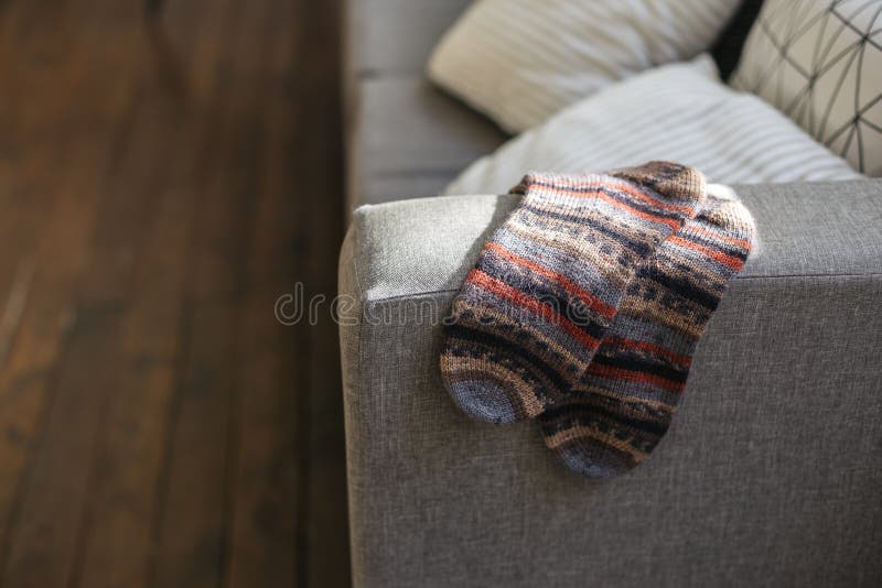 Pair of hand knitted socks on the sofa in modern interior. Natural colors. Pair of hand knitted socks on the sofa in modern interior. Natural colors