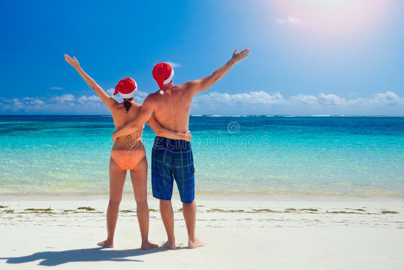 Par i santa& x27; s-hattar på en tropisk strand arkivbild Par i santa& x27; s-hattar på en tropisk strand arkivbild