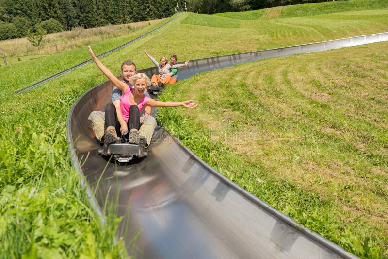 Excited young couples enjoying alpine coaster luge during summer. Excited young couples enjoying alpine coaster luge during summer