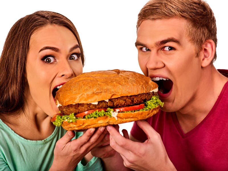 Couple eating fast food. Man and women treat big hamburger with ham. Friends give burder junk on white background isolated. Enamored people eat huge sandwich. Couple eating fast food. Man and women treat big hamburger with ham. Friends give burder junk on white background isolated. Enamored people eat huge sandwich.