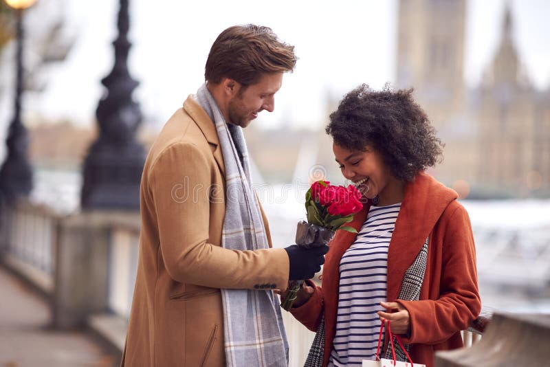 Para jesienią lub jesienią spotkanie na randce w mieście z mężczyzną dającym kobiecie bukiet kwiatów