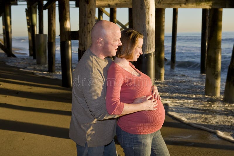 Pregnant Couple looking at the Sunset on Beach. Pregnant Couple looking at the Sunset on Beach