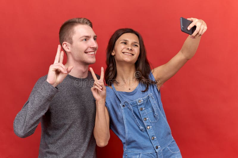 Para två vänner som gör en selfie på telefonen, lyckligt ler och ser in i kamera på isolerad bakgrund arkivfoto Para två vänner som gör en selfie på telefonen, lyckligt ler och ser in i kamera på isolerad bakgrund arkivfoto