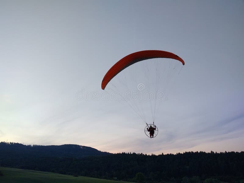 Padákový kluzák létání na padáku při západu slunce na louce.