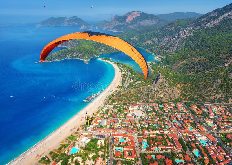 Paraglider tandem flying over the sea with blue water and mounta