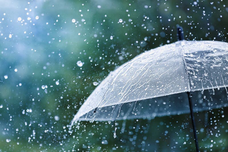 Mujer con paraguas de colores bajo la lluvia en el campo Stock Photo