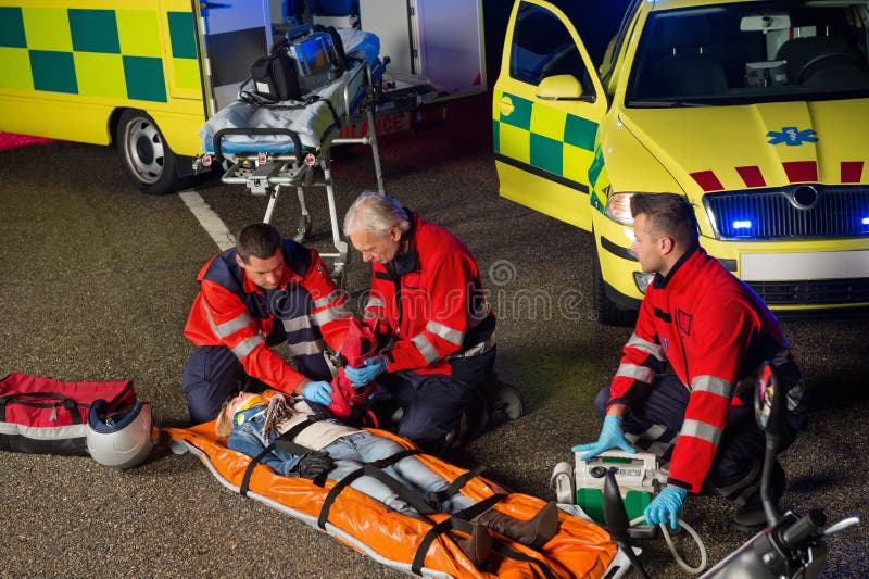 Paramedici che aiutano il driver della motocicletta sulla barella immagini stock libere da diritti Paramedici che aiutano il driver della motocicletta sulla barella immagini stock libere da diritti