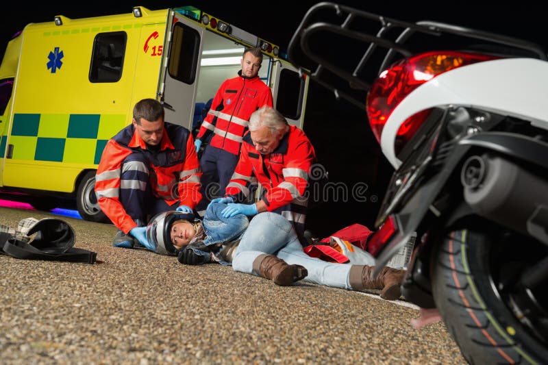 Paramédicos que ajudam o motorista de motocicleta ferido imagens de stock Paramédicos que ajudam o motorista de motocicleta ferido imagens de stock