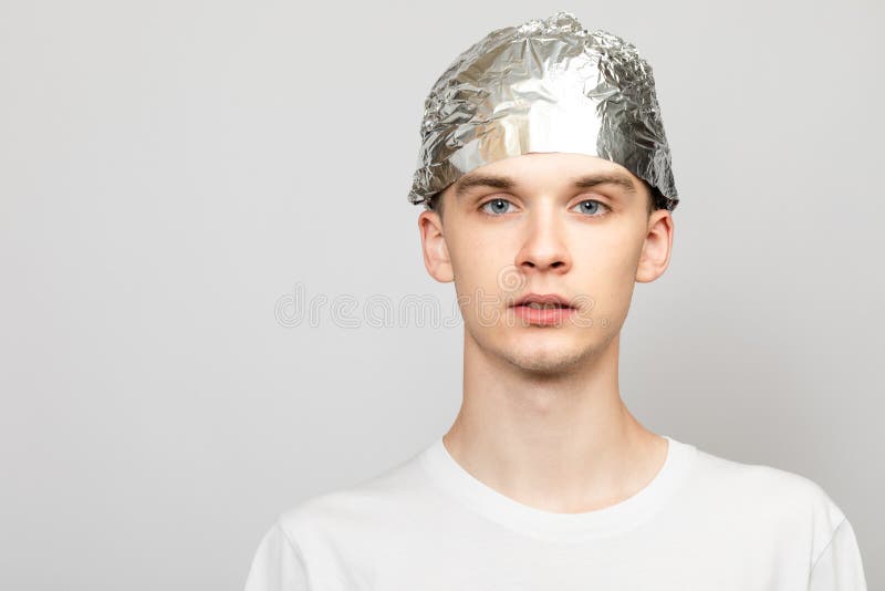 Paranoid Young Man Wearing Tin Foil Hat Studio Shot on Gray Background