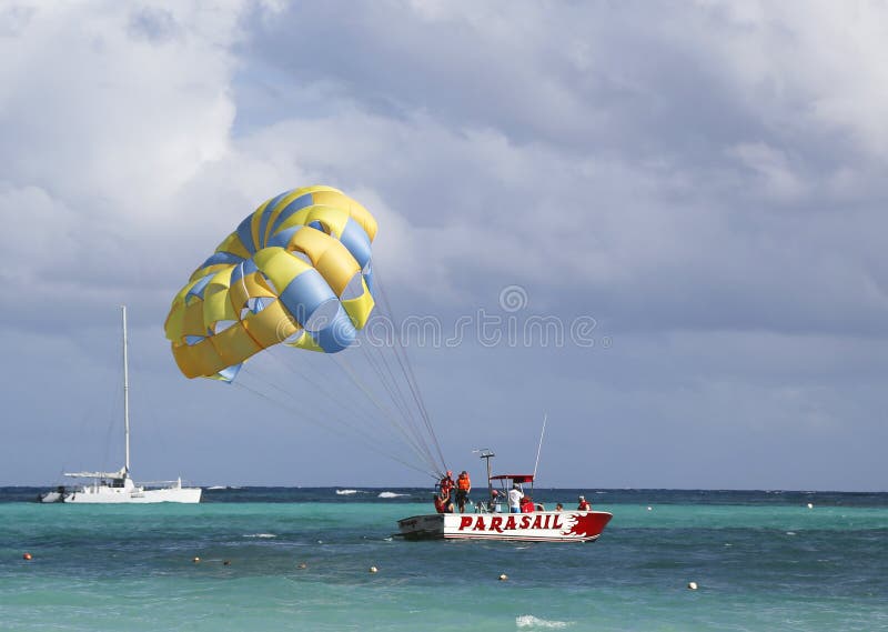 PUNTA CANA, DOMINICAN REPUBLIC - DECEMBER 31: Parasailing in a blue sky in Punta Cana on December 31, 2013. Parasailing is a popular recreational activity among tourists in Dominican Republic. PUNTA CANA, DOMINICAN REPUBLIC - DECEMBER 31: Parasailing in a blue sky in Punta Cana on December 31, 2013. Parasailing is a popular recreational activity among tourists in Dominican Republic